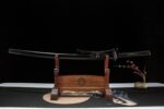 Buddha and Demon sword, black scabbard and black-red hilt katana, displayed on wooden stand as an art collectible.