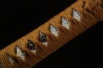 Golden Dragon Blade handle close-up, showcasing traditional wrapping, menuki, and ray skin texture