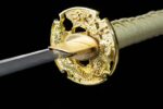 Half-Tachi, close-up of the katana's golden openwork tsuba, featuring intricately carved dragon reliefs, perfectly integrated with the blade base, showcasing its artistry and function.