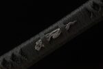 Buddha and Demon Sword handle detail, metal menuki visible under black diamond-patterned tsuka-maki. Flame-like design adds artistic flair.