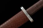 Wind Messenger sword, close-up of brown scabbard and hilt connection, showcasing metal guard and leather texture.