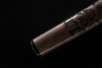 Demon-killing Sword scabbard close-up, dark wood grain and sheen.