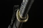 Night Blade sword, close-up of golden ornate tsuba and black hilt, showcasing intricate guard design and functional carrying strap.