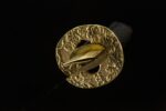 Emperor's Golden Blade golden tsuba close-up, openwork or embossed texture, enhancing sword aesthetics.