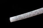 White Lotus Knife scabbard bottom end close-up, showcasing its smooth white surface and blue or black ink-splash pattern extending to the tip.