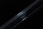 Messer broadsword blade close-up, black high carbon steel, glossy finish and blade texture details, showing cutting edge.
