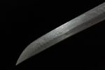 Close-up of the curve of the tip of a black Damascus Japanese sword