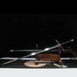 Lightweight European sword, an angled display of the unsheathed sword on a wooden stand, showing the complete shape of the blade, handle, and guard.