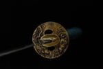 Red Night Sword round tsuba close-up, displaying intricate carved texture