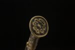 Longming Sword hilt end, showing its circular pattern and metallic luster.