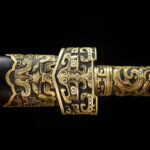 Imperial Sword, a close-up of the hilt-to-scabbard joint, showing brass fittings, detailed carving, and seamless connection design.
