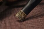 Chibi Xiaohan Sword, close-up of the scabbard end, showing the intricate brass carving decoration and classic texture.