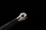 Lightweight European sword, a close-up of the pommel, showcasing its classic spherical design and smooth metal texture.