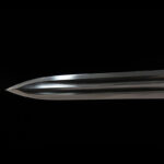 Dragon God Sword tip, finely honed edge, sharp point, close-up detail highlighting forging quality.